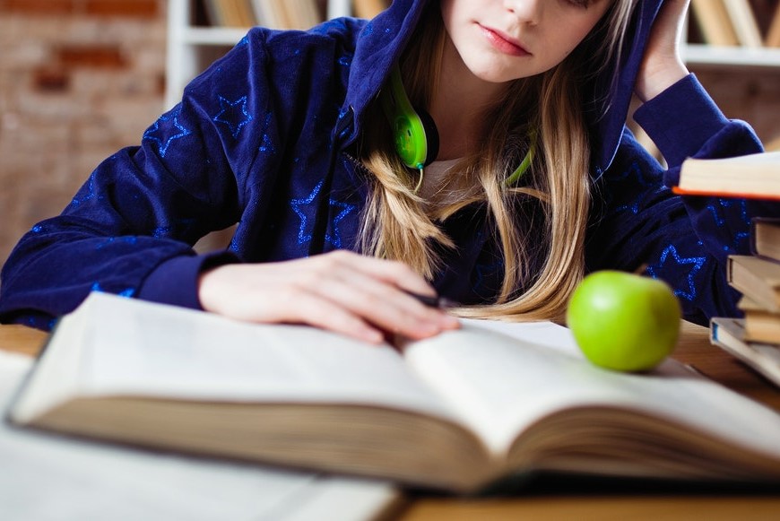 girl studying with an apple on her book